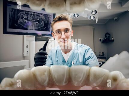 Calm smiling. Doctor looking into mouth, checking, examining teeth. Using professional tools and equipments. Healthcare and medicine, stomatology, feelings of patient. Look from inside the teeth. Stock Photo