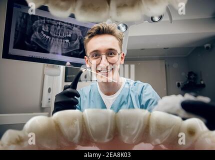 Calm smiling. Doctor looking into mouth, checking, examining teeth. Using professional tools and equipments. Healthcare and medicine, stomatology, feelings of patient. Look from inside the teeth. Stock Photo