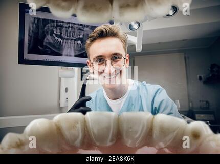 Calm smiling. Doctor looking into mouth, checking, examining teeth. Using professional tools and equipments. Healthcare and medicine, stomatology, feelings of patient. Look from inside the teeth. Stock Photo