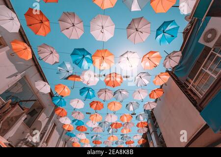 Pedestrian street with colorful multi-colored umbrellas as decoration and protection from the bright sun at noon. Stock Photo
