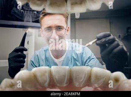 Calm smiling. Doctor looking into mouth, checking, examining teeth. Using professional tools and equipments. Healthcare and medicine, stomatology, feelings of patient. Look from inside the teeth. Stock Photo