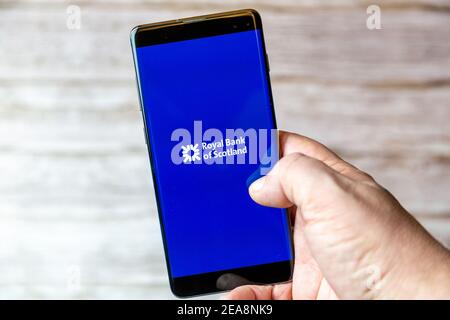 A mobile phone or cell phone being held in a hand with the Royal bank of scotland app open on screen Stock Photo