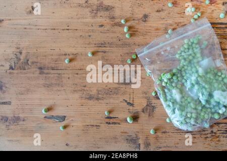 Fresh frozen peas in plastic bag on wood table. Plastic bag with frozen green peas on wooden background. Homemade preparations for cooking. Healthy ve Stock Photo