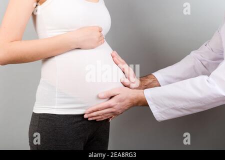 Happy doctor caring about young pregnant woman. doctor using hand examining pregnant woman in clinic. Stock Photo