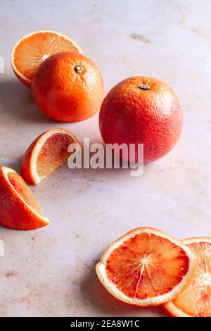 Fresh blood orange, whole, halved, quartered and sliced, on a pink marble backdrop. Stock Photo