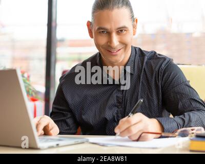 Middle aged man during online video call. He looking at camera and smiling. Web meeting with friends or business partners. Stock Photo