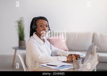 Pretty black woman listening to webinar from home Stock Photo