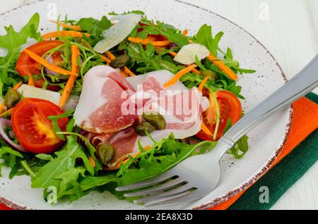 Plate with fresh salad leaves, parmesan slices and jamon. Studio Photo Stock Photo
