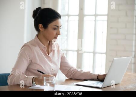 Focused young Indian business woman working on computer Stock Photo