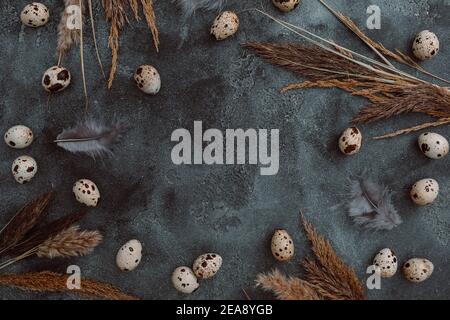 Stylish frame with Easter eggs with reeds foliage branches on dark background. Flat lay, Top view. Easter holiday concept. Stock Photo