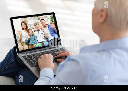 Elderly woman using laptop to speak to her children and grandkids online from home, making video call with relatives Stock Photo
