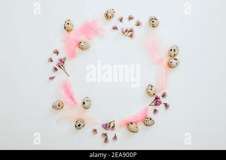 Ester frame composition with quail eggs and pastel feathers on white background. Flat lay, top view Stock Photo