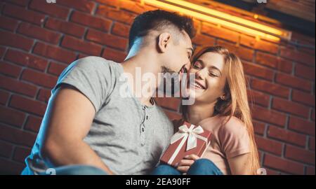 Caucasian man is kissing his girlfriend while giving her a present dating on valentines day Stock Photo