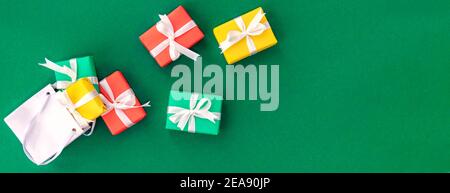 Banner with fallen paper bag with scattered gifts. Red, green and yellow gifts in shopping bag on green background with space for text. Christmas and Stock Photo