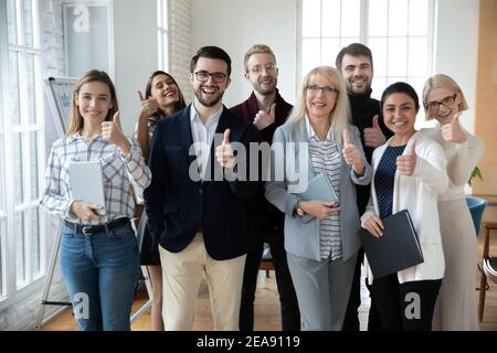 Portrait of successful mature businesswoman and team showing thumbs up Stock Photo