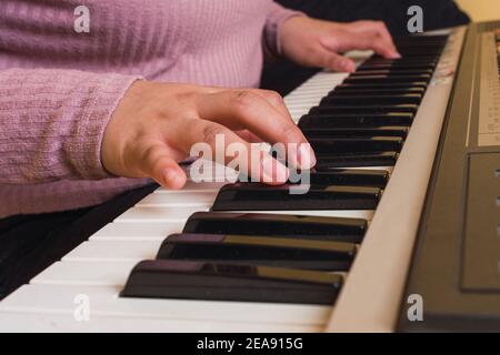 two hands of a young girl playing a piano in a purple sweater Stock Photo