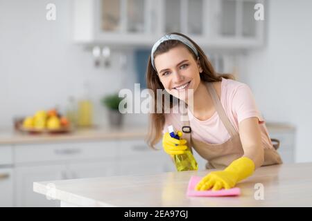 https://l450v.alamy.com/450v/2ea97gj/happy-housewife-or-maid-cleaning-table-with-rag-and-detergent-at-kitchen-copy-space-professional-sanitary-service-2ea97gj.jpg
