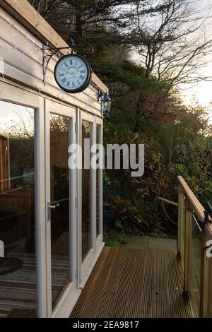 Kirkcudbright, Scotland - December 24, 2020: A Kensington London clock hanging above a garden office in the late afternoon sun in winter Stock Photo
