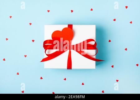 Trendy attractive minimalistic gift on the blue background with hearts. Merry Christmas, St. Valentine's Day, Happy Birthday and other holidays concept. Stock Photo