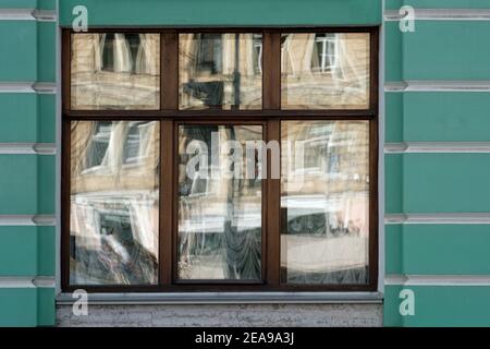 Reflections in the glass of a rectangular window against a green wall. From a series of windows of St. Petersburg. Stock Photo
