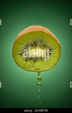 sliced kiwi fruit with dripping juice on green background Stock Photo