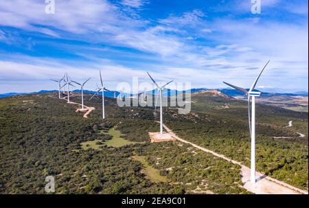 Wind turbines and curvy road on the hill, Wind farm Green ecological power energy generation. Alternative energy plant, blue cloudy sky, sunny day, Gr Stock Photo