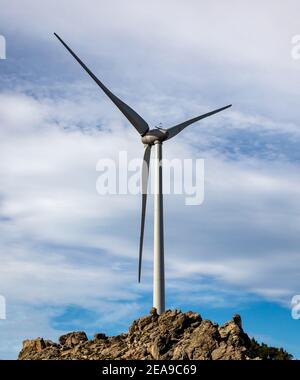 Wind turbine on a rocky hill in the Australian outback against a blue ...