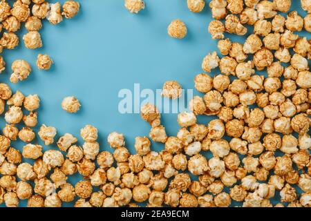 Popcorn is scattered on a blue background, in the form of a frame. Yummy for the filming of movies, TV series, cartoons. Free space, top view Stock Photo