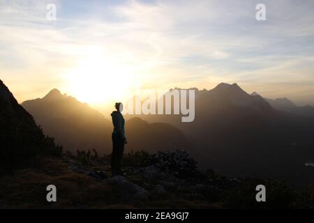 young woman in the sunset towards the Wettersteingebirge, Arnspitze, in the background the Zugspitze, taken on Gamseck above the Mittenwalder Hut Stock Photo