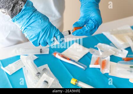 High angle of crop unrecognizable medic in latex gloves preparing syringe for injection in hospital Stock Photo