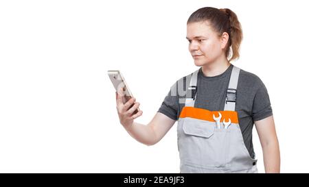 an employee in a gray uniform overalls with a wrench in his pocket holds a tablet mobile device for online service and purchases of goods, plumber iso Stock Photo