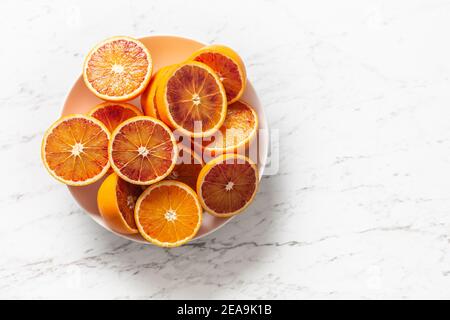 Sliced red oranges in a plate on a marble white table - top of view. Stock Photo