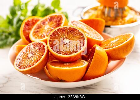 Blood sicilian oranges sliced on white plate with fresh melissa Stock Photo