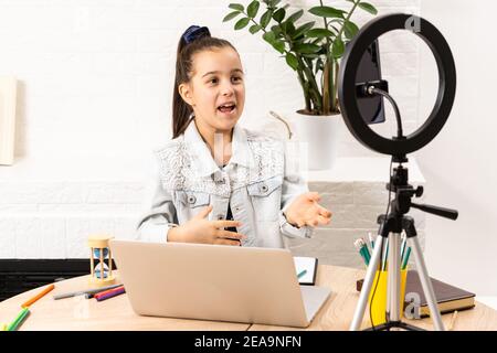 Cute little beauty blogger. Girl speaking in front of camera for vlog. Stock Photo