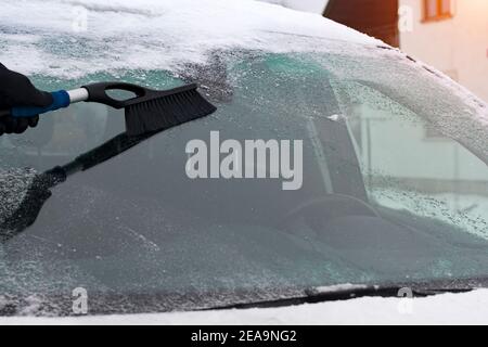Winter scene, human hand in glove scraping ice from windshield of car Stock Photo