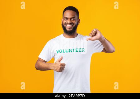 Smiling african volunteer man pointing thumbs at himself, yellow background Stock Photo