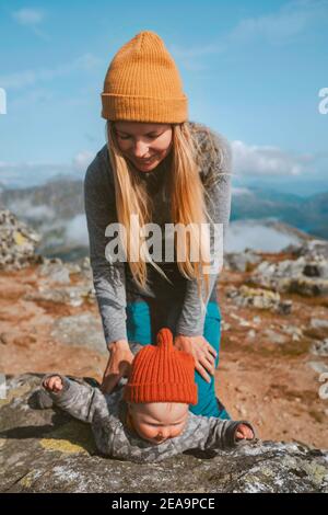 Mother with baby playing outdoor family travel lifestyle vacations infant child learning crawling autumn season trip in Norway Stock Photo