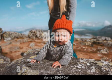 Baby traveler crawling outdoor family lifestyle vacation activity infant child wearing orange hat autumn season trip in Norway Stock Photo