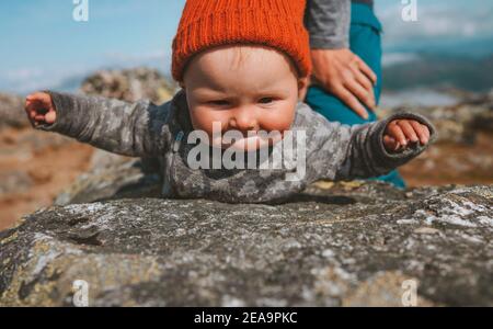 Baby balancing on rock outdoor family travel lifestyle vacation infant child wearing orange hat autumn season