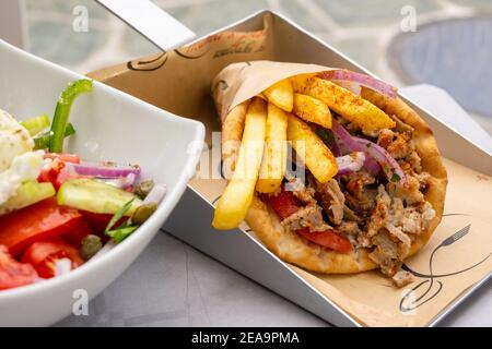 Folegandros, Greece - September 24, 2020: Traditional Greek souvlaki with chicken gyros, vegetables and fries served in pita bread. Stock Photo