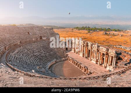 Ancient Greek amphitheater in the city of Hierapolis near Pamukkale in Turkey. Wonders and travel attractions. Hot air balloon above in the morning sk Stock Photo