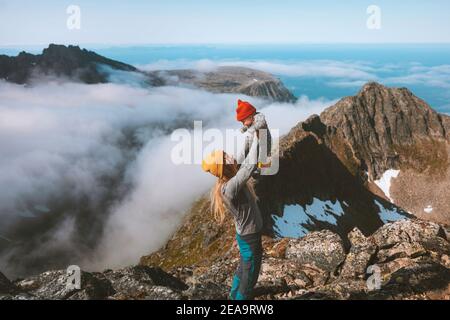Mother holding up infant baby family hiking in mountains vacations outdoor active woman mom with child healthy lifestyle trip in Norway Stock Photo