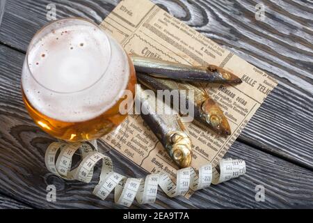 Beer in a glass and smoked fish. Nearby is a measuring tape. On pine boards.  A day without diets Stock Photo - Alamy