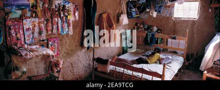 Child learning on her bed in simple hut, in a poor desert district of Venezuela; South America. Stock Photo