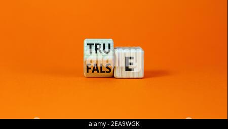 False or true symbol. Turned a wooden cube and changed the word 'false' to 'true' or vice versa. Beautiful orange table, orange background, copy space Stock Photo