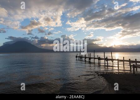 Lake Atitlan at Sunset. Silhouettes of a dock with San Pedro Volcano, Toliman Volcano and Antigua Volcano in the distance.