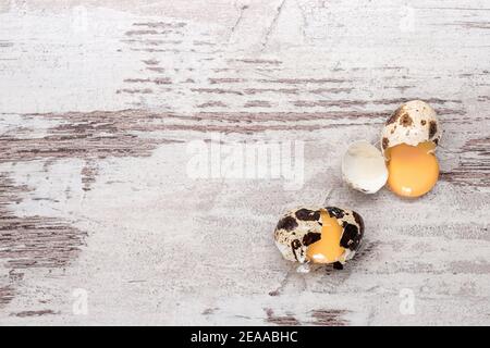 Two broken quail eggs on wooden table. Copy space, top view Stock Photo