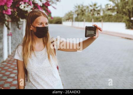 Coronavirus face mask protection woman taking selfie using smart phone covid-19 quarantine pandemic lockdown new normal lifestyle city life Stock Photo
