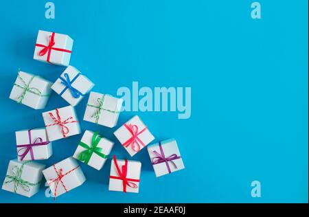 White boxes with colored ribbons lie on a blue background. Top view. Space for the text. Stock Photo