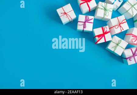 White boxes with colored ribbons lie on a blue background. Top view. Space for the text. Stock Photo